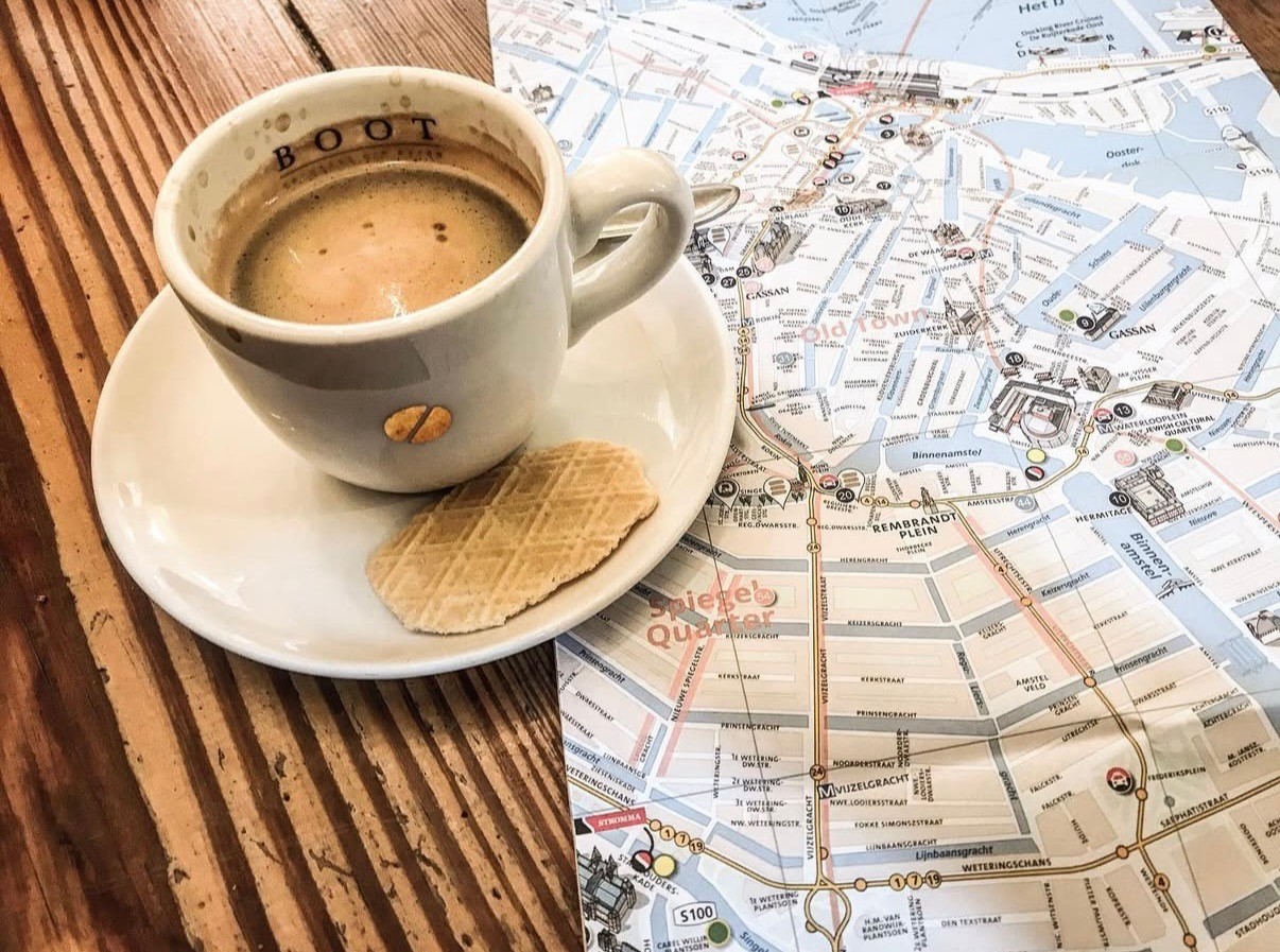 A cup of coffee, a biscuit, and a map of Amsterdam